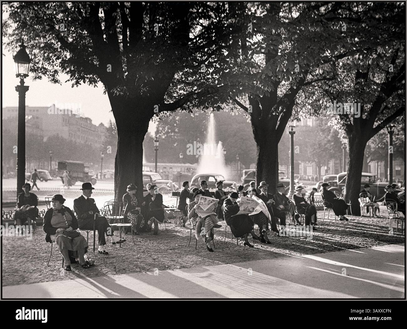 Jahrgang Vorkriegszeit 1935 Paris stilvolle Pariser Damen und Herren lesen die Zeitungen auf einer sonnigen Bank in der Nähe von Rond-Point an der Champs-Elysee Datum : 1935 Ort : Frankreich, Paris Wilhelm van de Poll Stockfoto