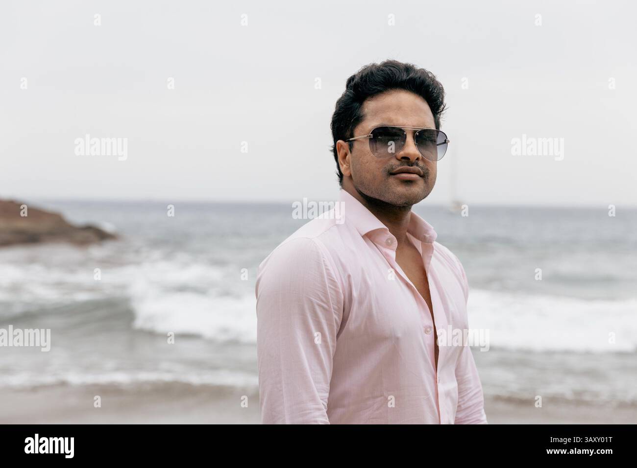 Porträt eines attraktiven erfolgreichen Indianers am Strand während des Urlaubs. Stockfoto