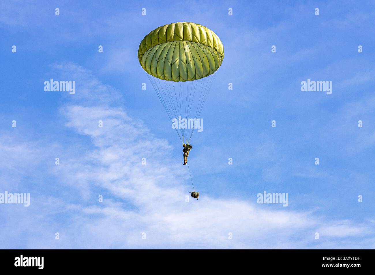 Deutsche Fallschirmjäger während einer NATO-Übung, die mit Fallschirmen durch den Himmel absteigen. Eine Darstellung von Präzision, Training und Koordination in einem Dynami Stockfoto