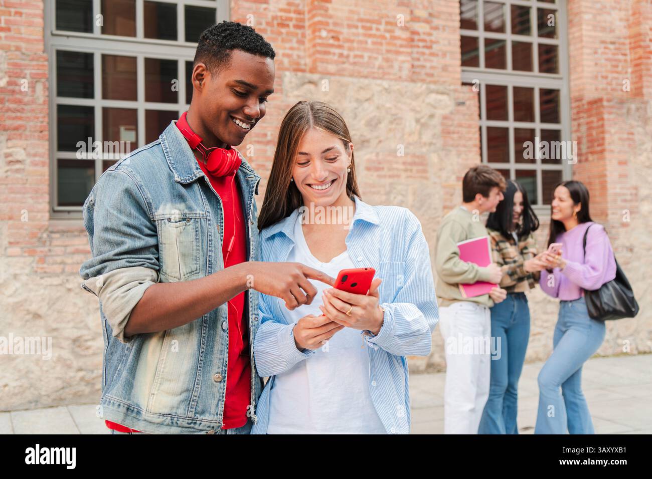Junge Freunde teilen spannende Momente mit Freude, während sie ein Smartphone verwenden, um ansprechende Anwendungen zu erkunden und sich in lebendiger Atmosphäre miteinander zu verbinden Stockfoto