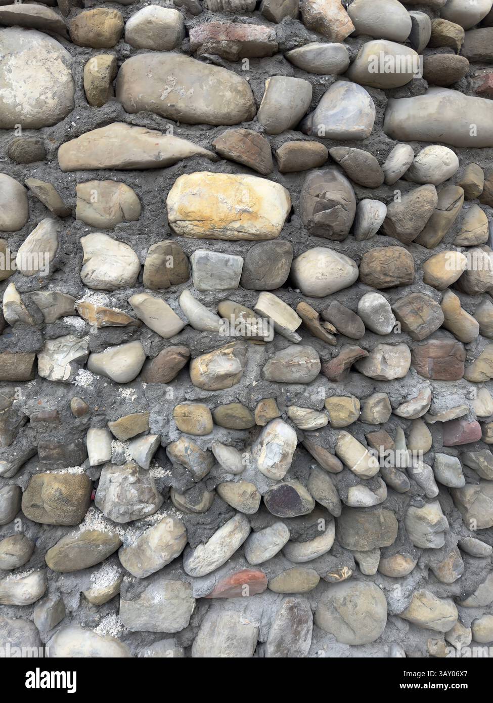 Rustikale Steinwand mit natürlicher Witterung, ideal für Hintergründe, Architekturprojekte und Vintage-Designs. Erdtöne und raue Muster - Smartphone-aufgenommenes Stockfoto