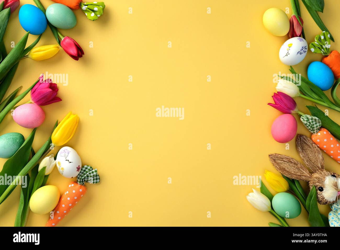 Happy Easter-Konzept. Flache Lay-Komposition mit bunten Tulpen und Ostereiern, Häschen, Karotten auf gelbem Hintergrund. Osterrahmen, Grußkarte Temp Stockfoto