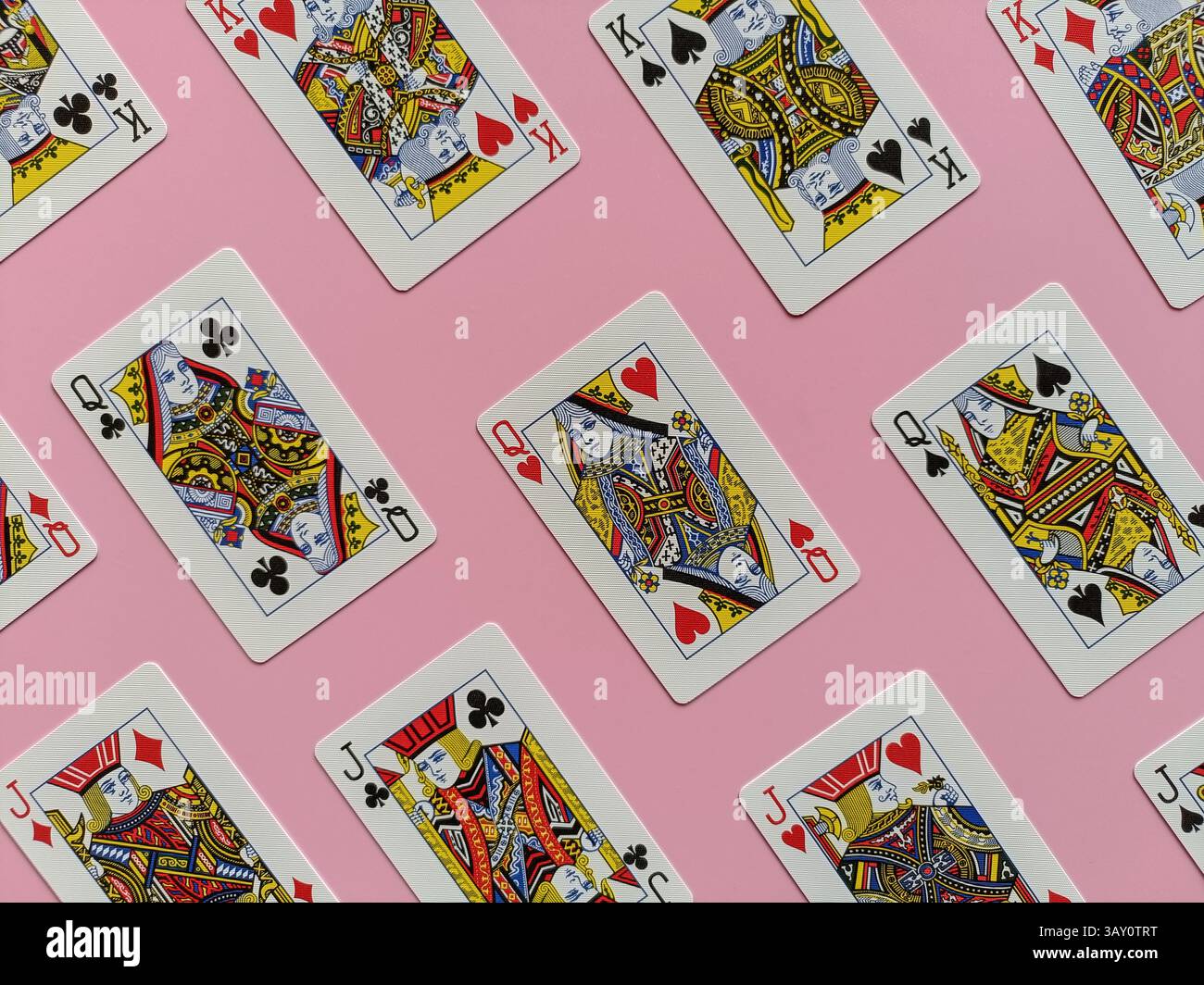 Spielkarten vor einem rosafarbenen Hintergrund. Jede Karte ist in Anzug und Farbe unterschiedlich und zeigt komplizierte Designs und traditionelle Hoffiguren - Smartphone-aufgenommenes Stockfoto