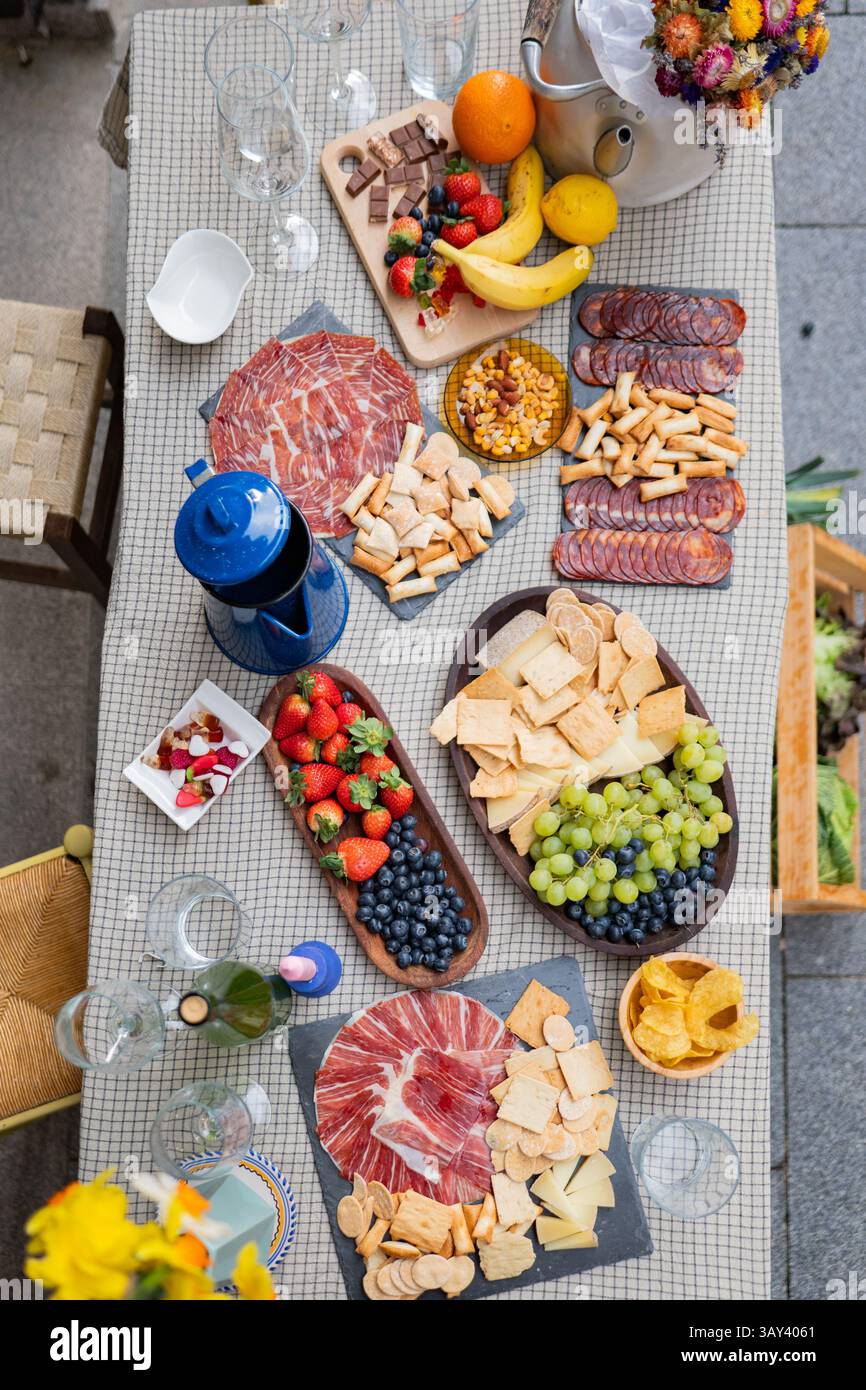 Ein bezaubernder Tisch im Freien mit frischem Obst, Wurstwaren, Snacks und verschiedenen Käsesorten. Bietet ein einladendes Ambiente, das perfekt für Arbeitstreffen geeignet ist Stockfoto