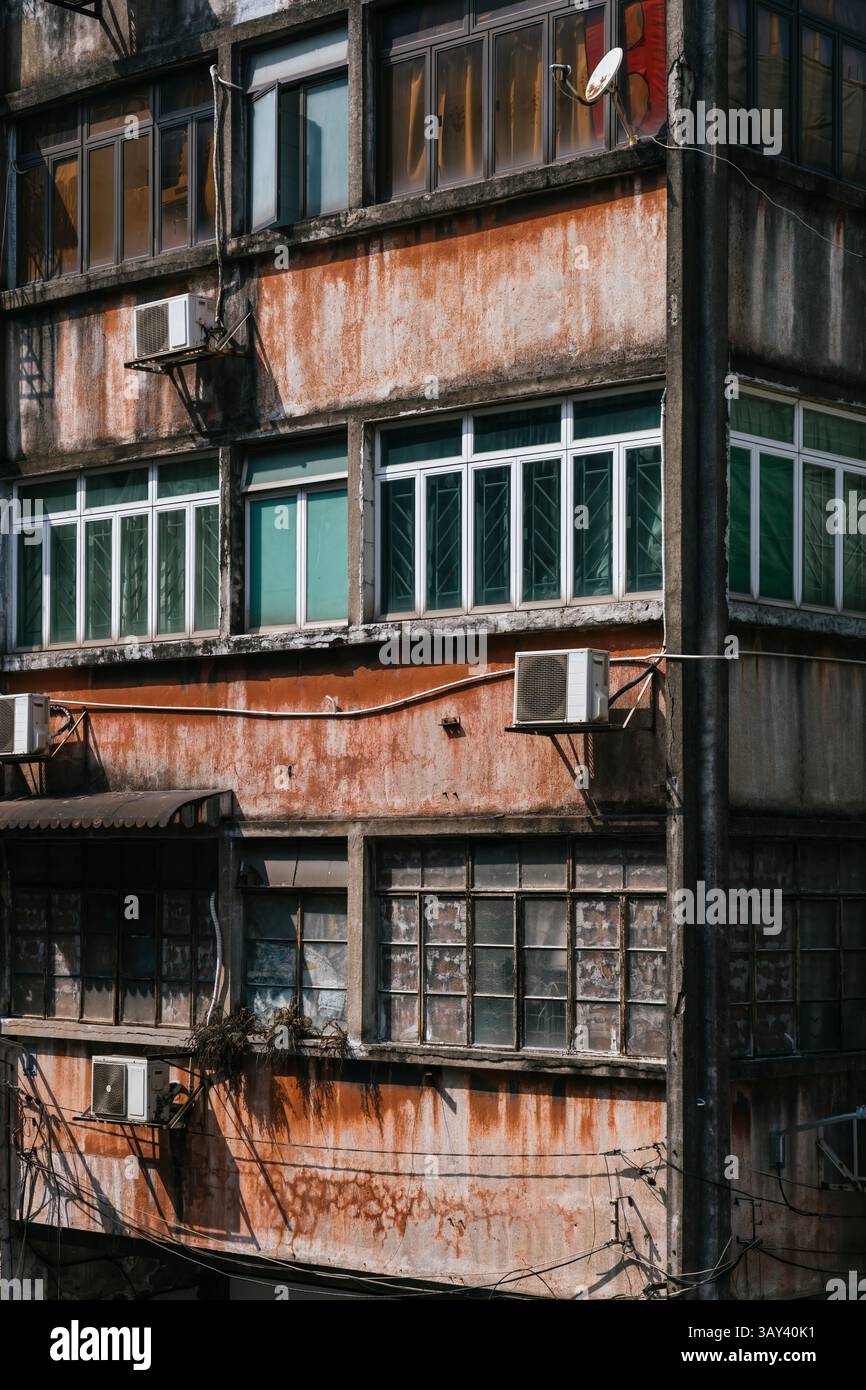 Nahaufnahme einer alten Gebäudefassade mit vergitterten Balkonen und Fenstern für Sicherheit und Schutz vor Taifunen, im urbanen Kontext erfasst Stockfoto