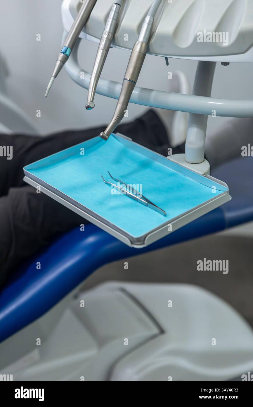 Nahaufnahme zahnärztlicher Instrumente auf einem Tablett in einer Zahnarztpraxis. Enthält auf einem blauen Pad angeordnete Werkzeuge, die für zahnärztliche Eingriffe bereit sind. Stockfoto
