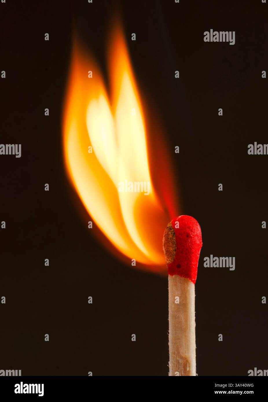 Ein Nahaufnahme-Foto eines Streichholzstifts, das eine leuchtende orangene Flamme vor dunklem Hintergrund erzeugt und das Wesen von Entzündung und Wärme einfängt. Stockfoto