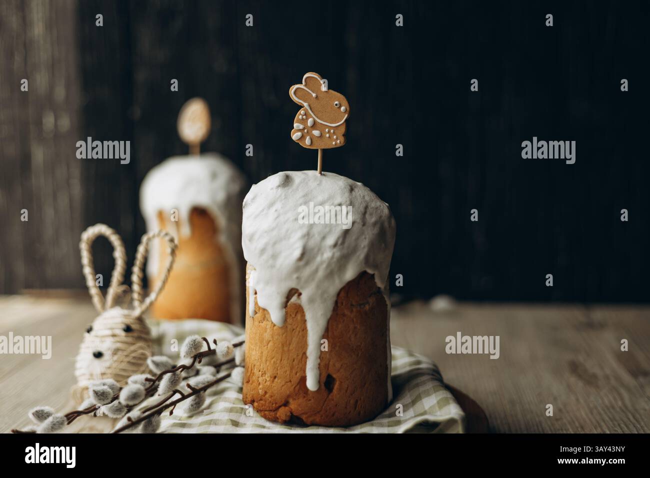Traditionelles russisches Kulich-Brot mit weißer Glasur und süßen Osterdekorationen, präsentiert auf einem rustikalen Holztisch für einen festlichen Feiernden Stockfoto