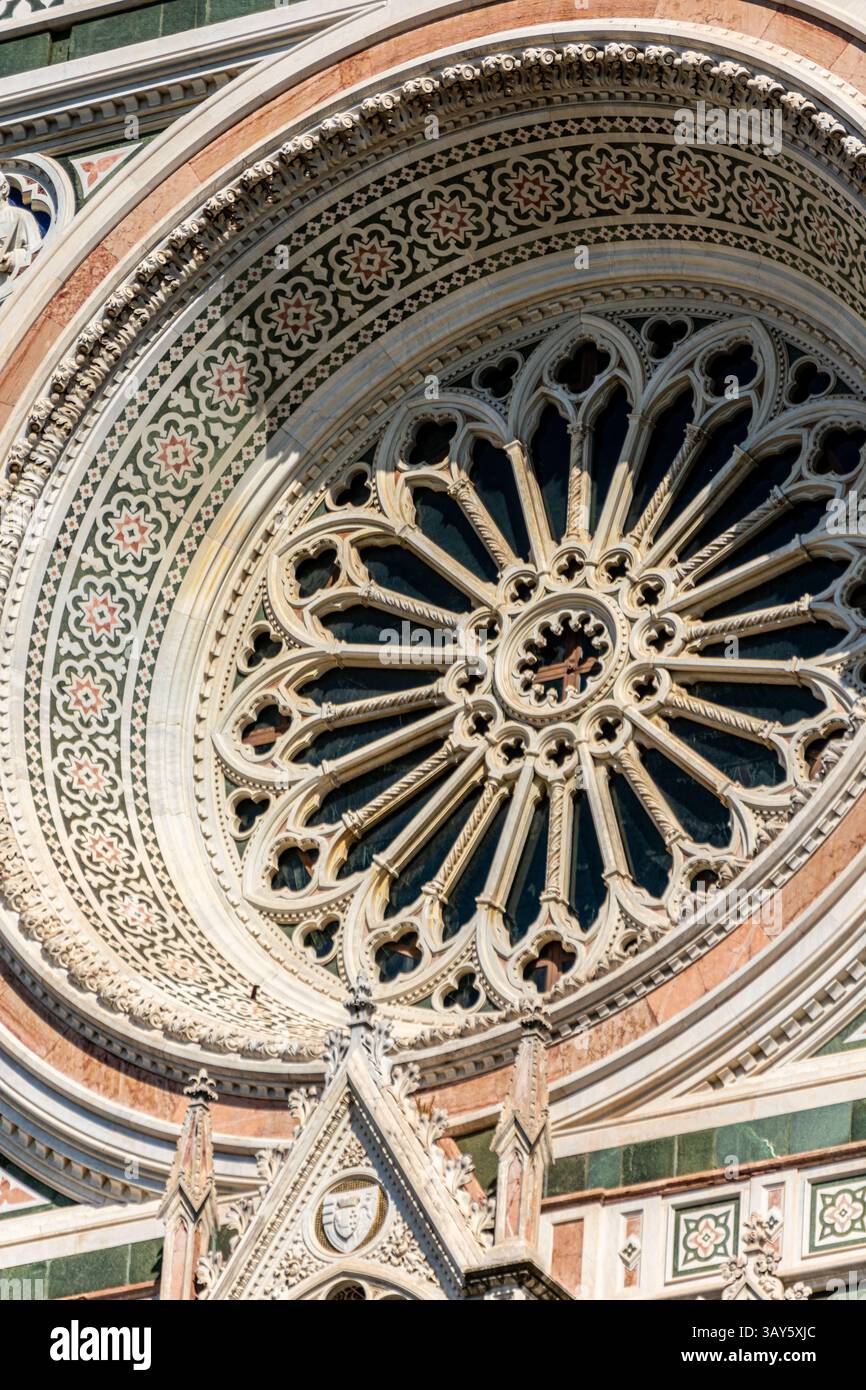 Blick aus nächster Nähe auf das Rosenfenster und dekorative Marmoreinlagen an der Westfassade von Santa Maria del Fiore, Florenz, Italien. Stockfoto
