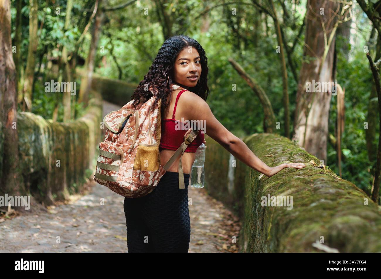 Eine junge Frau erkundet freudig einen üppigen Pfad, der den Geist des Abenteuers und die Schönheit der Natur umfasst Stockfoto