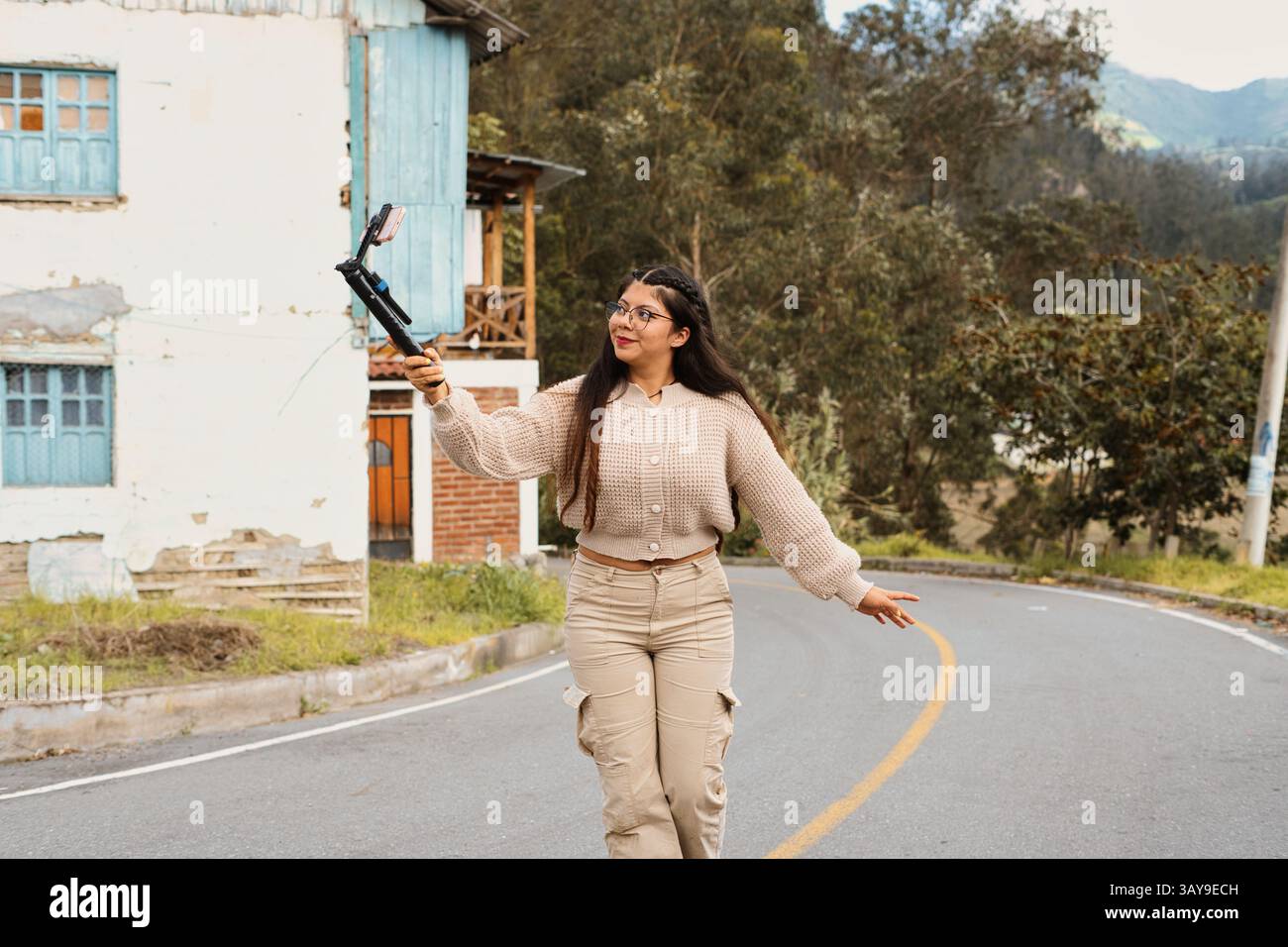 Eine junge Frau genießt gerne einen gemütlichen Spaziergang mit einem Selfie-Stick in einer wunderschönen und malerischen Umgebung im Freien Stockfoto
