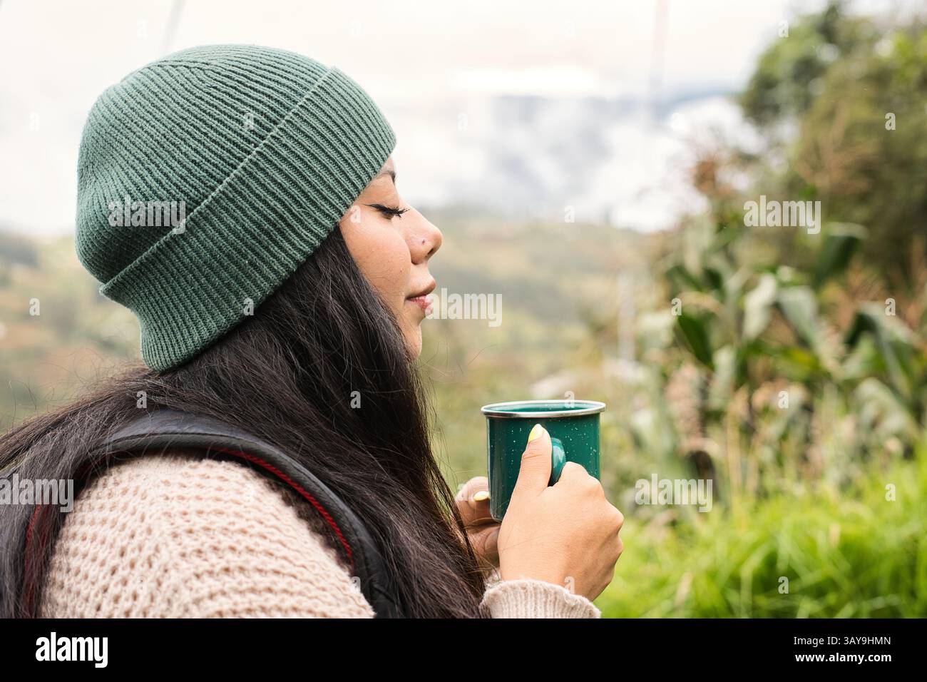 Eine Frau, die draußen ein köstliches warmes Getränk genießt und die Ruhe und den Frieden der Natur in vollen Zügen genießt Stockfoto