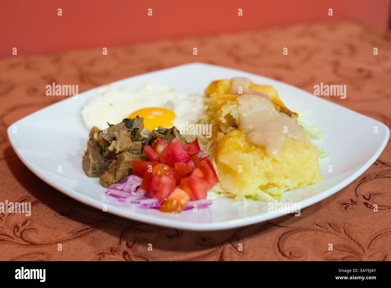 Eine farbenfrohe Mahlzeit mit herzhaften Elementen, frischem Gemüse und einem elegant servierten Ei auf einem weißen Teller Stockfoto