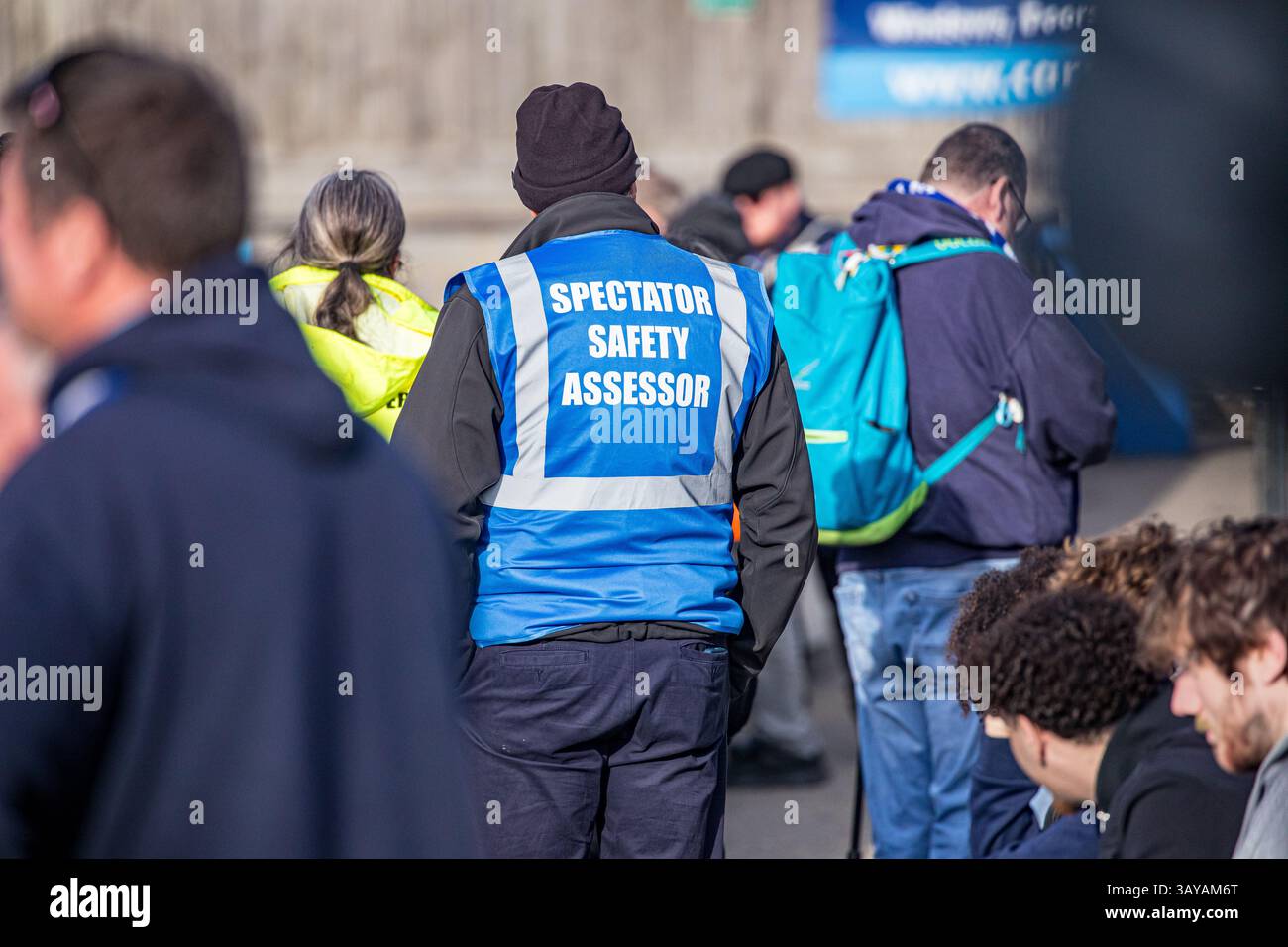 Zuschauersicherheitsbewerter, der bei einem Fußballspiel in einer blauen, gut sichtbaren Jacke durch die Massen der Fans läuft Stockfoto