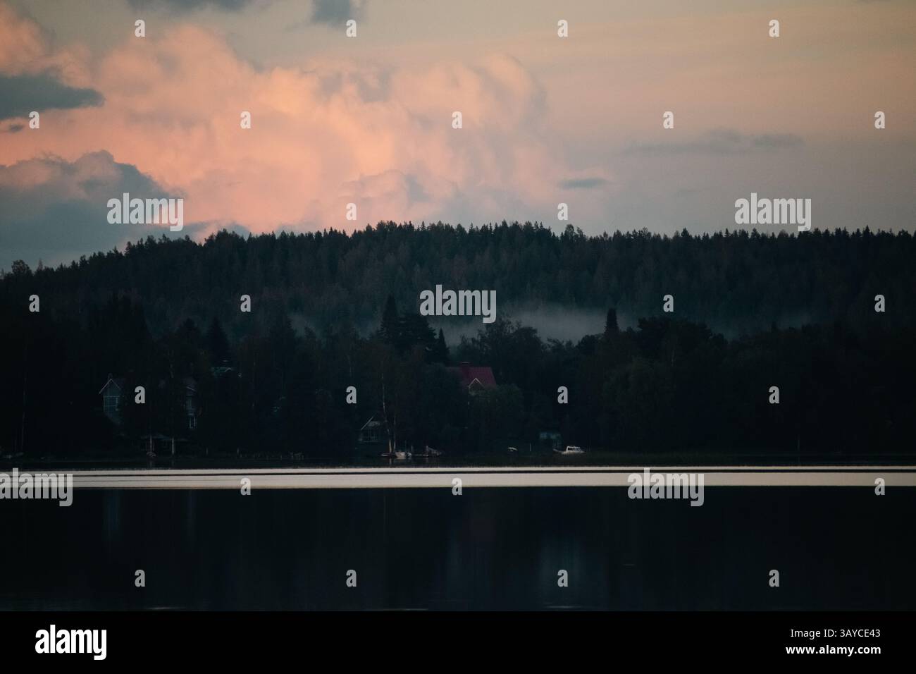 Ein bedeckter Spätsommer mit einer Hütte am Horizont über einem ruhigen See. Stockfoto