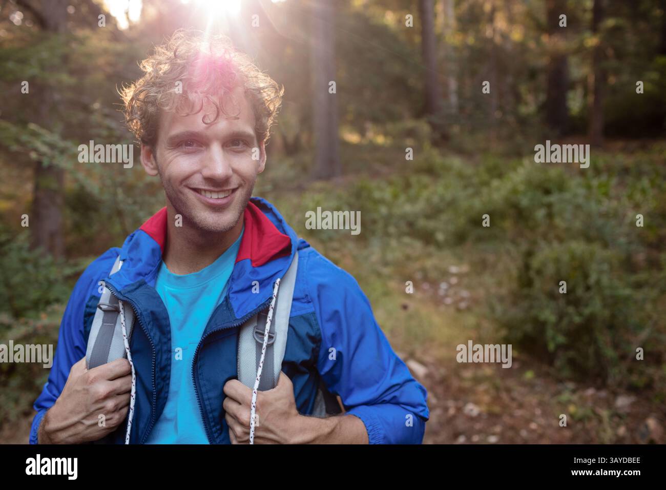 Mann Mitte Zwanzigerjahre Wanderweg am späten Nachmittag mit blauer Jacke, Rucksack, Kopierraum Stockfoto
