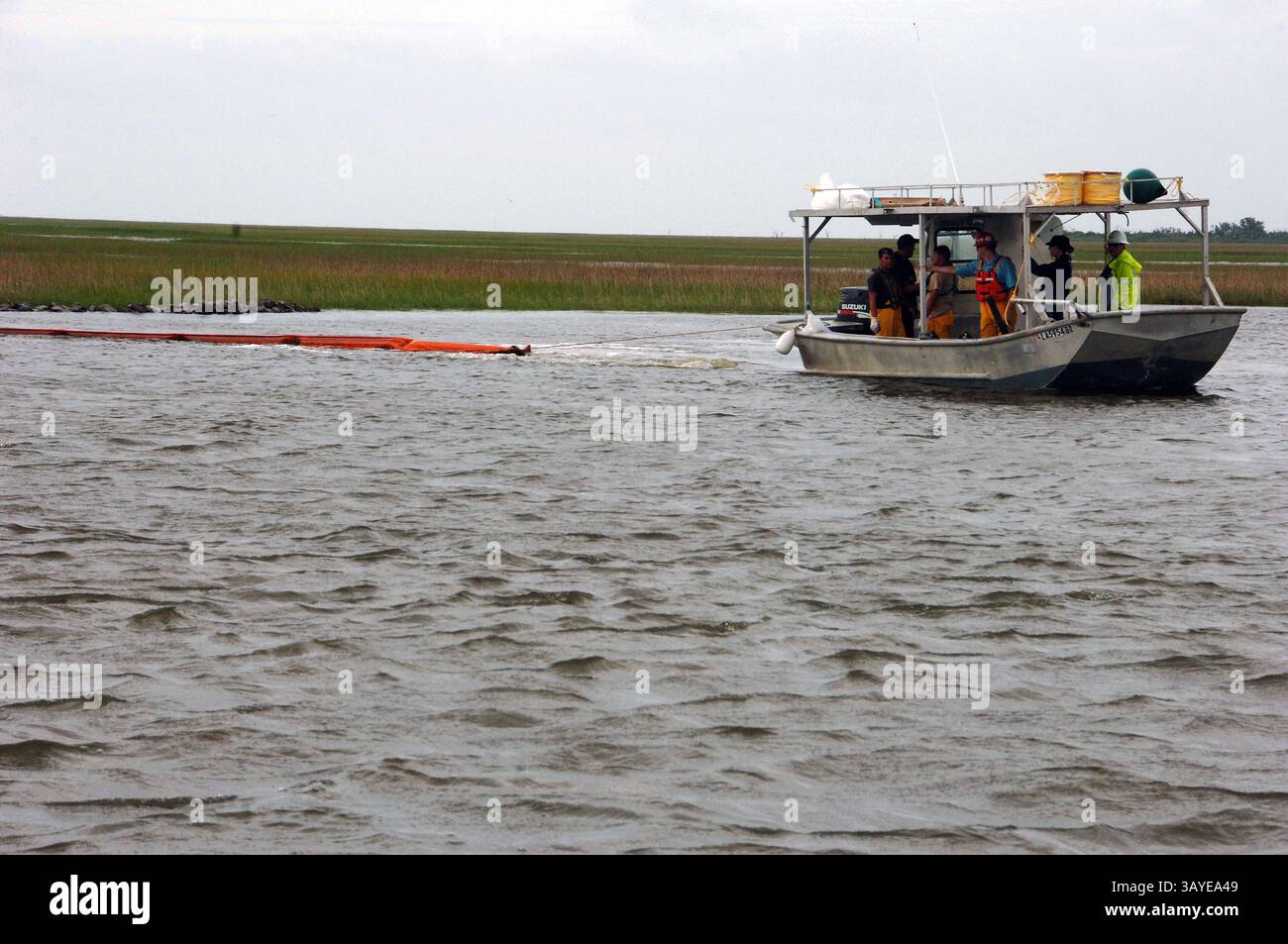 29. Juni 2010 – Lake Barre, Louisiana, USA – Ein Arbeitsboot zieht einen harten Boom über einen Pass zwischen Sumpfgras in Lake Barre, La, während die äußeren Bänder des Tropical Storm Alex am Dienstag den Himmel verdunkeln. Da das schlechte Wetter durch den Sturm die Bedingungen für den Wasserbetrieb in den nächsten Tagen unsicher machen könnte, schlossen Bauunternehmer und Mitarbeiter der Küstenwache aus Branch Terrebonne Parish, La. Pässe mit diesen schwimmenden Barrieren ab, um zu verhindern, dass Öl, das vom Deepwater Horizon in den See gelangt, tief in die Sümpfe eindringt. Das Deepwater Horizon Öl Stockfoto
