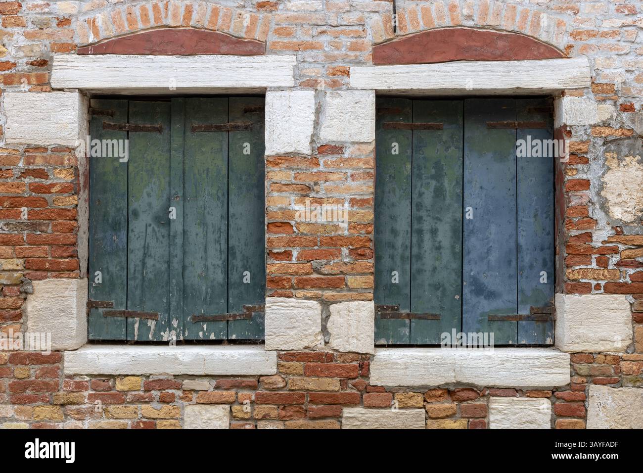 Alte Holzläden an der Ziegelmauer Stockfoto