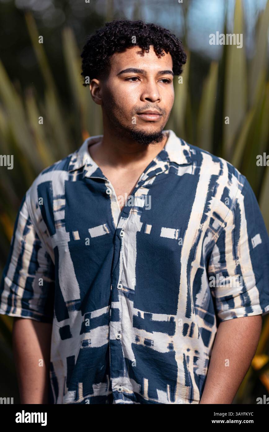 Selbstbewusster junger Mann, der in natürlichem Licht im Freien wegschaut Stockfoto