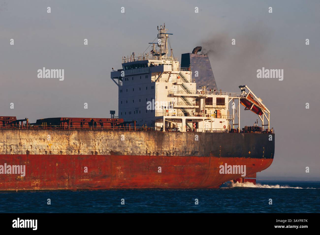 Rückansicht eines großen Frachtschiffes, das während der goldenen Stunde über das offene Meer segelt Stockfoto