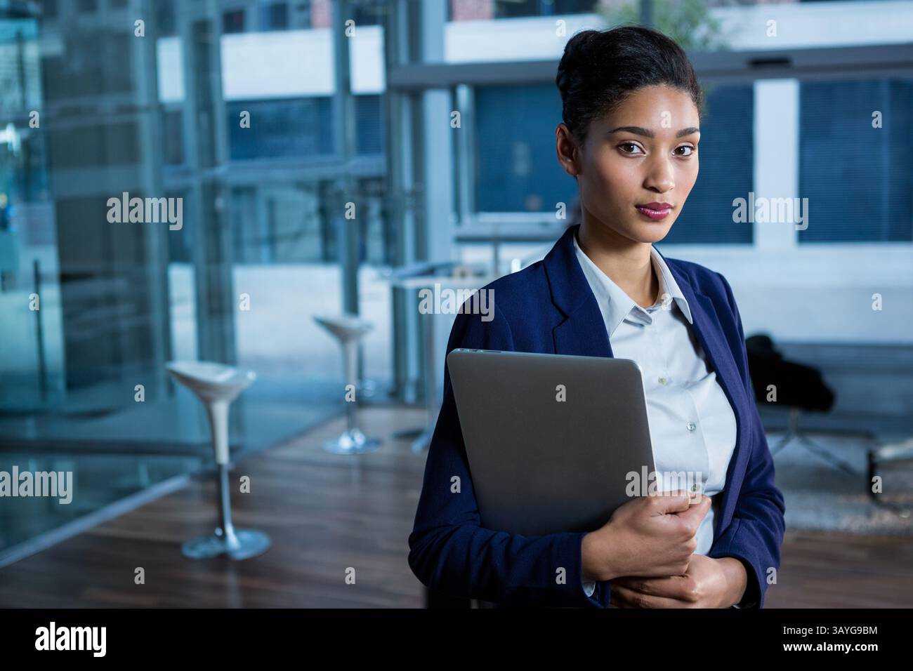 Professionelle Frau mit geschlossenem Laptop in der modernen Bürolounge mit Glaswänden und Kopierraum Stockfoto
