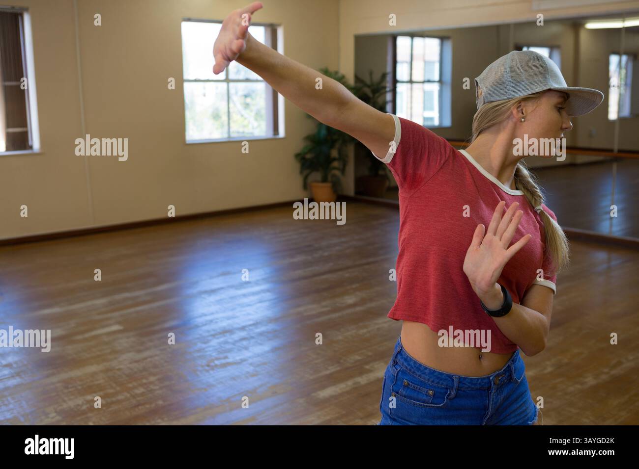 Auffällige Tanzposien der Frau im geräumigen Studio mit Holzboden und Spiegelwänden, Kopierraum Stockfoto