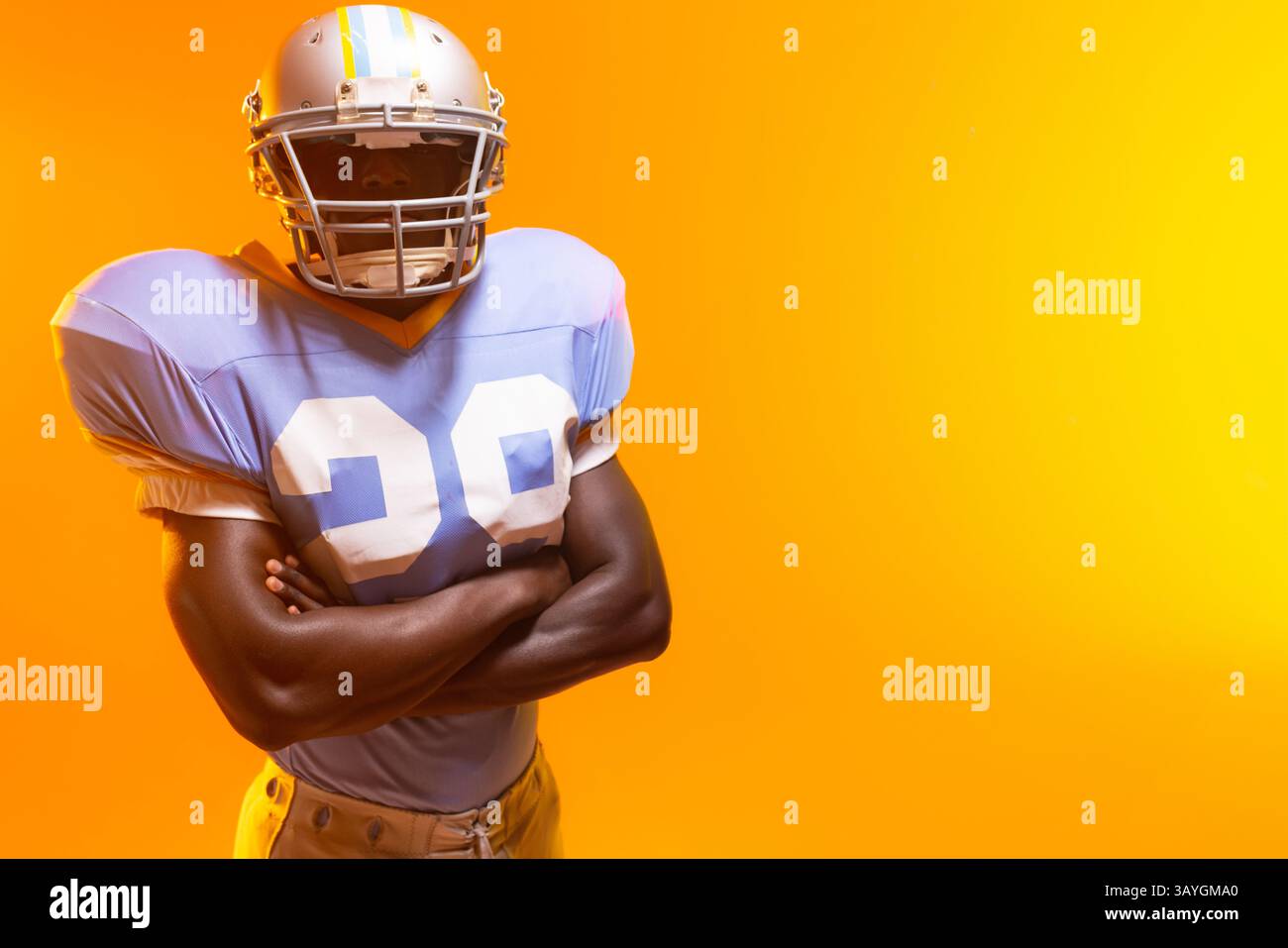 Afroamerikanischer Fußballspieler, der im Studio die Arme kreuzt, Helm und Polster trägt, Kopierraum Stockfoto