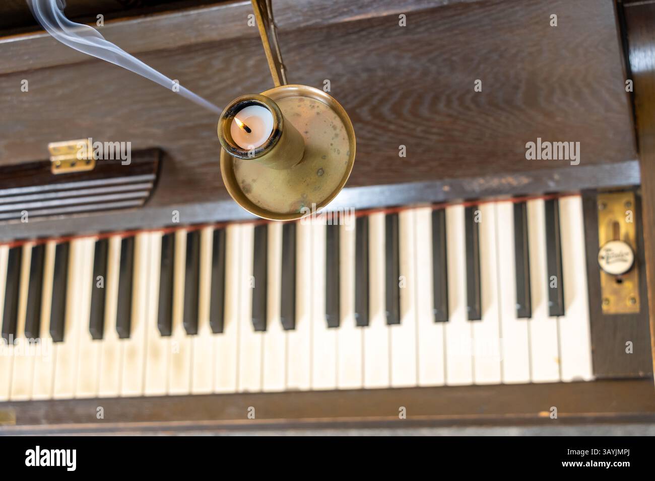 Brennende Kerze mit Rauch über den Orgelschlüsseln Stockfoto