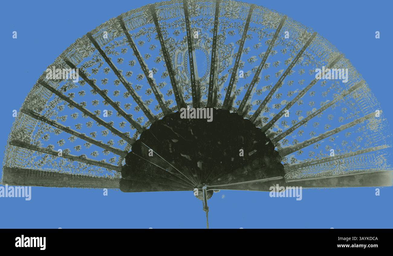 Ein aufwendig gestalteter Handventilator zeigt zarte Spitzenmuster und verzierte Details, ergänzt durch einen auffälligen blauen Hintergrund. Fan, ca. 1875, England, schwarze Schnürhalterung, glatte Schildkröte-Muschelstangen und -Schutzvorrichtungen, Muschelschlaufe und ein Metallniet, 26,7 cm 26,7 cm (10 1/2 Zoll) Klassische Kunst mit modernem Touch, neu interpretiert von Artotop Stockfoto
