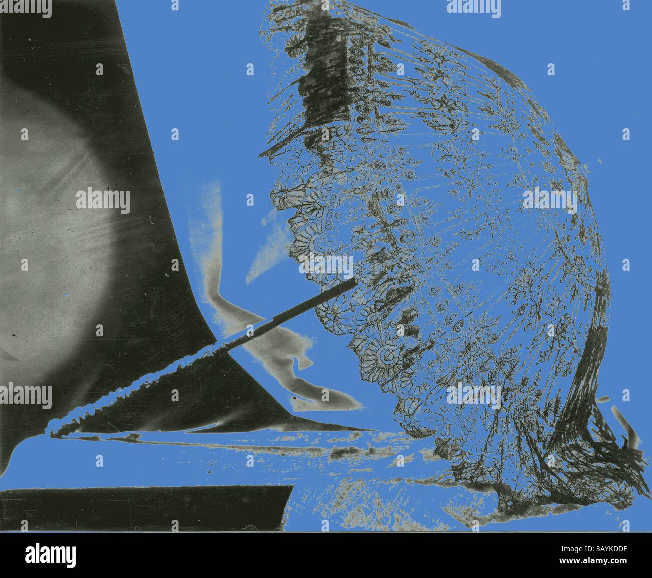 Ein aufwändig gestalteter Spitzenschirm liegt elegant vor einem leuchtend blauen Hintergrund und wirft zarte Schatten, die seine kunstvollen Muster und Texturen unterstreichen. Sonnenschirm, um 1870, Frankreich, Schwarze Chantilly-Spitze über weißer Sura, mit dünner schwarzer Seide gefüttert, gerader elfenbeinfarbener Griff mit Trauben und Blättern. Stahlrahmen, schwarz emaillierte Rohre, moderne Befestigung Klassische Kunst mit modernem Twist, neu interpretiert von Artotop Stockfoto