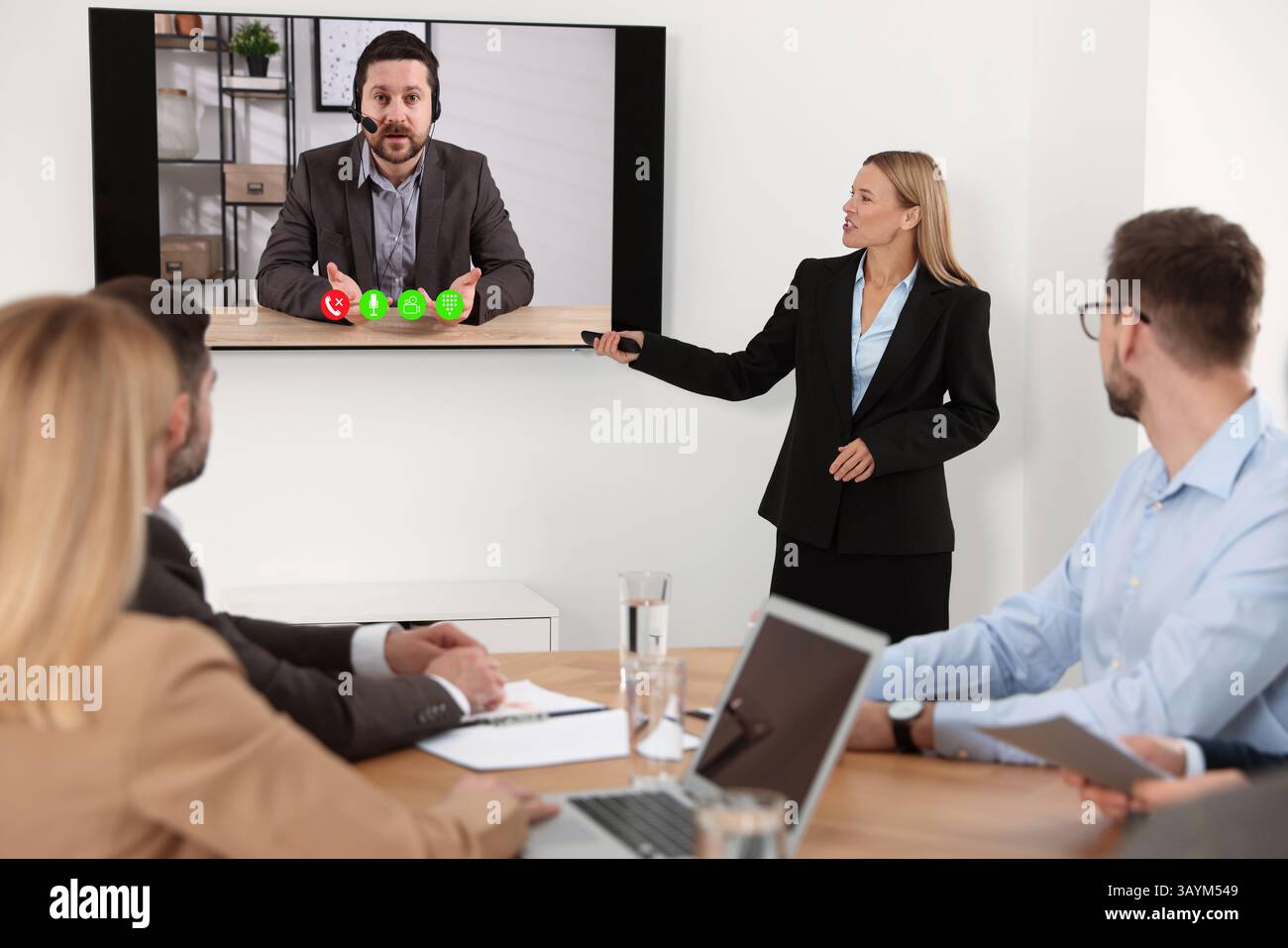 Redner, der über Online-Videochat an der Vorlesung teilnimmt. Publikum und Trainer im Konferenzraum mit Fernseher Stockfoto