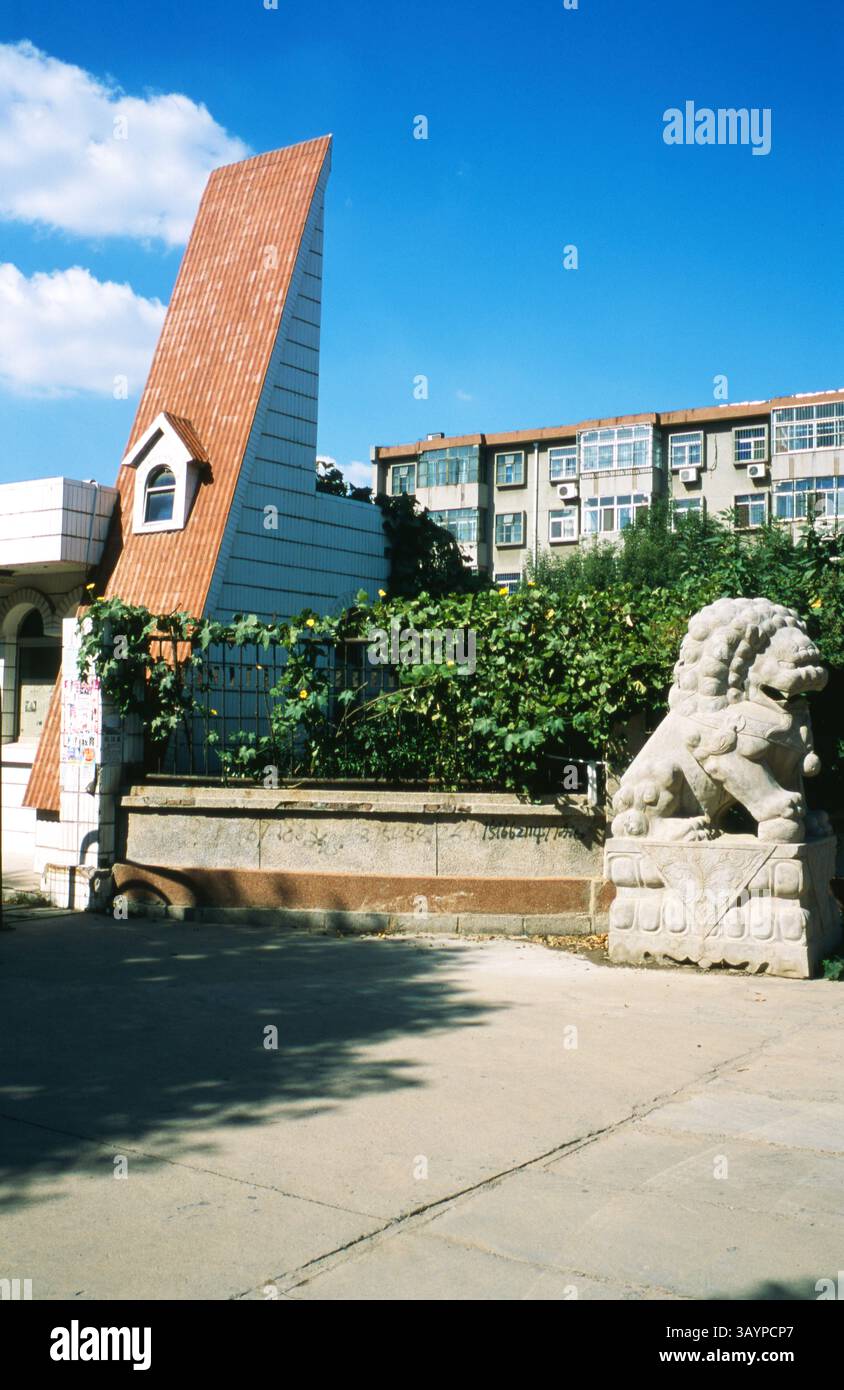 Einzigartiges architektonisches Design mit geneigtem Dach und Wächterlöwen-Statuen in urbaner Umgebung bei hellem Tageslicht: Vintage 1980er Jahre Park Gate mit gekacheltem Giebelturm und Stone Guardian Lion in Dongying, Shandong, 2010er Jahre Stockfoto