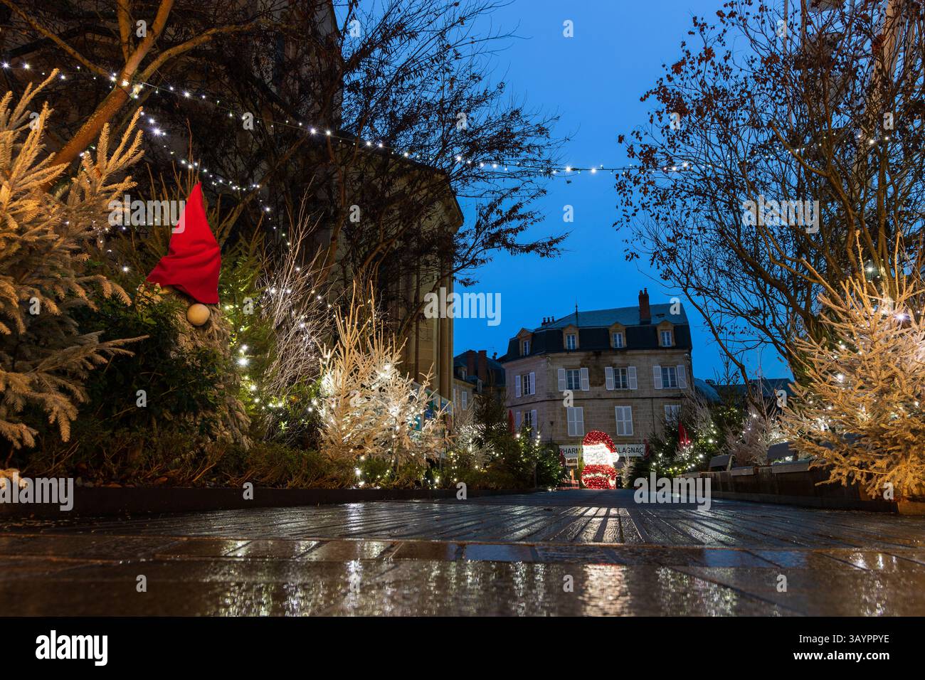 Ein Pfad entlang einer zentralen Dorfkirche, dekoriert für Weihnachten und Neujahr am frühen Morgen. Brive-la-Gaillarde, Frankreich. Stockfoto