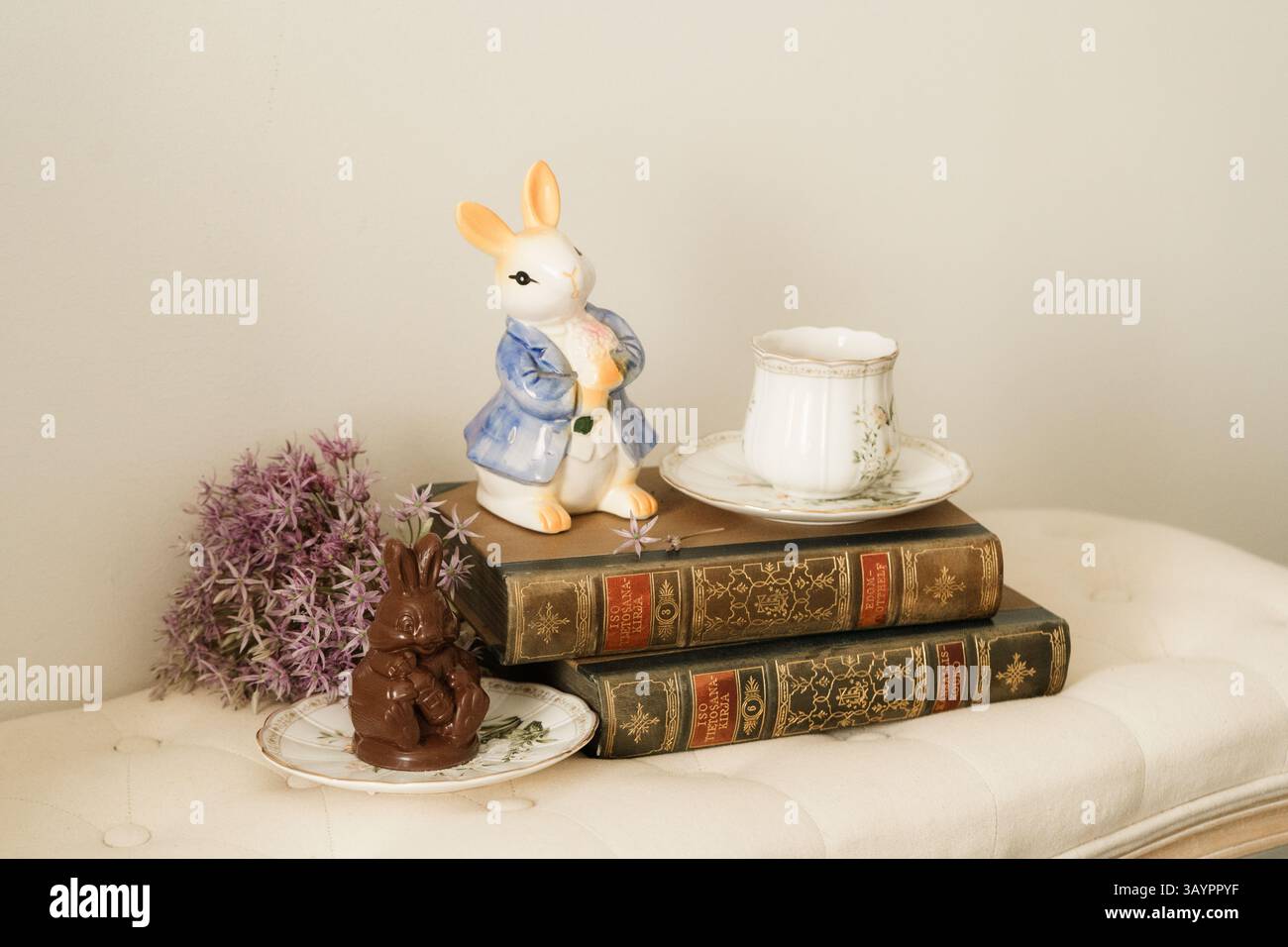 Alte Bücher, eine Tasse Kaffee und eine Kaninchenfigur auf dem Sofa Stockfoto