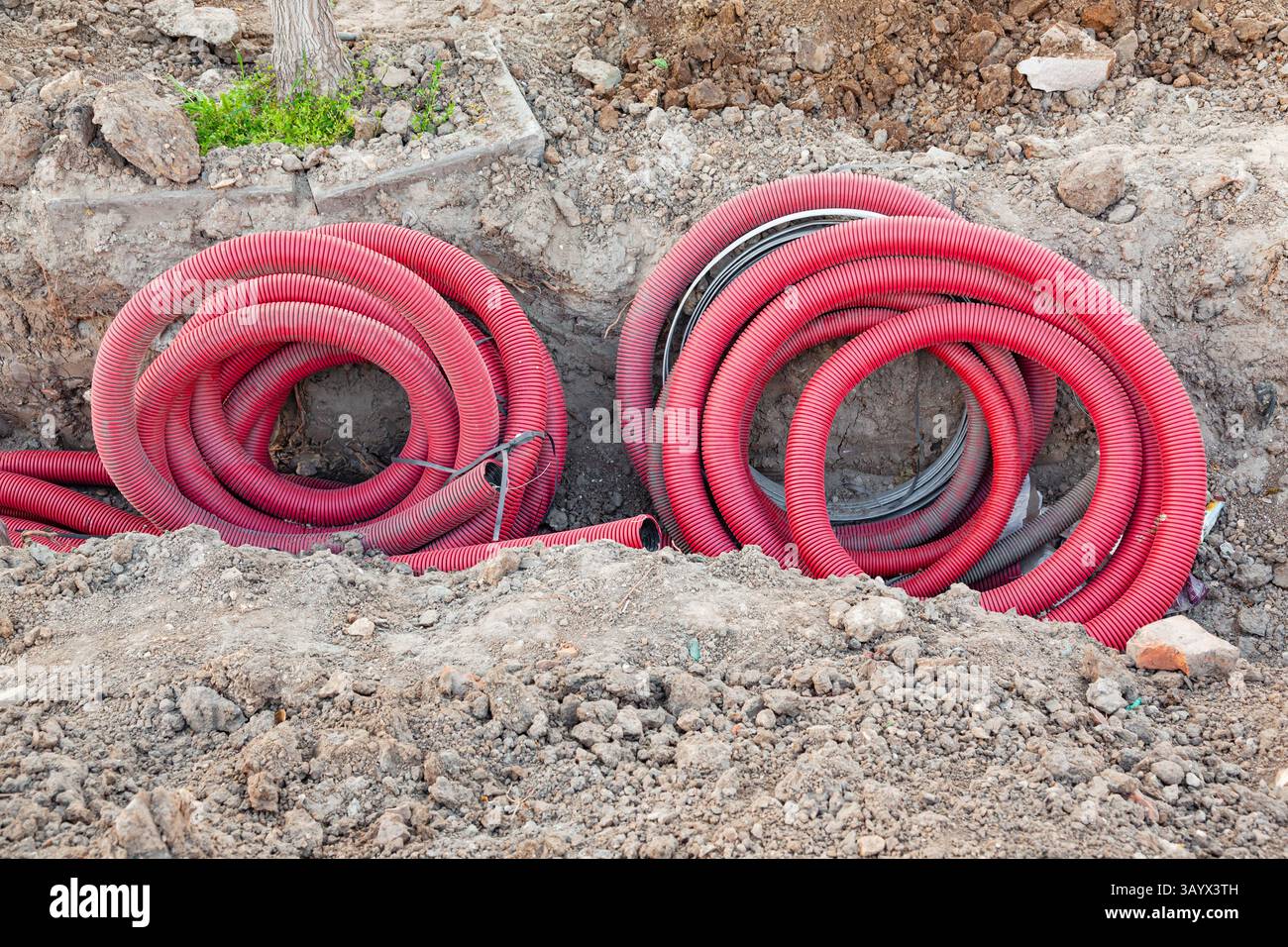 Verlegung der Kommunikation in den Boden mit roten Wellschläuchen. Stockfoto