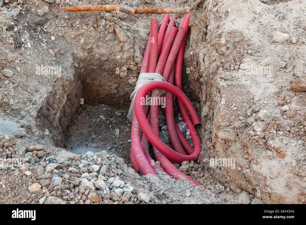 Verlegung der Kommunikation in den Boden mit roten Wellschläuchen. Stockfoto