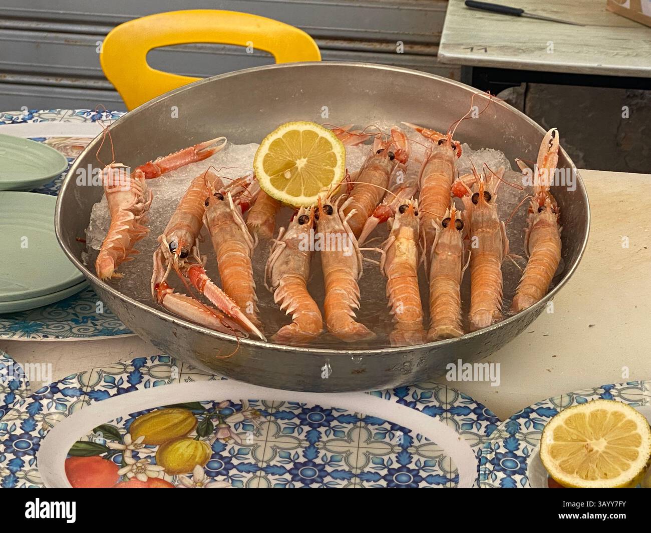 Frische Nephrops norvegicus, auch bekannt als Kaisergranat oder Scampi, serviert auf einem Eisbett mit einer Scheibe Zitrone, bereit für die Zubereitung in einem Restaurant Stockfoto