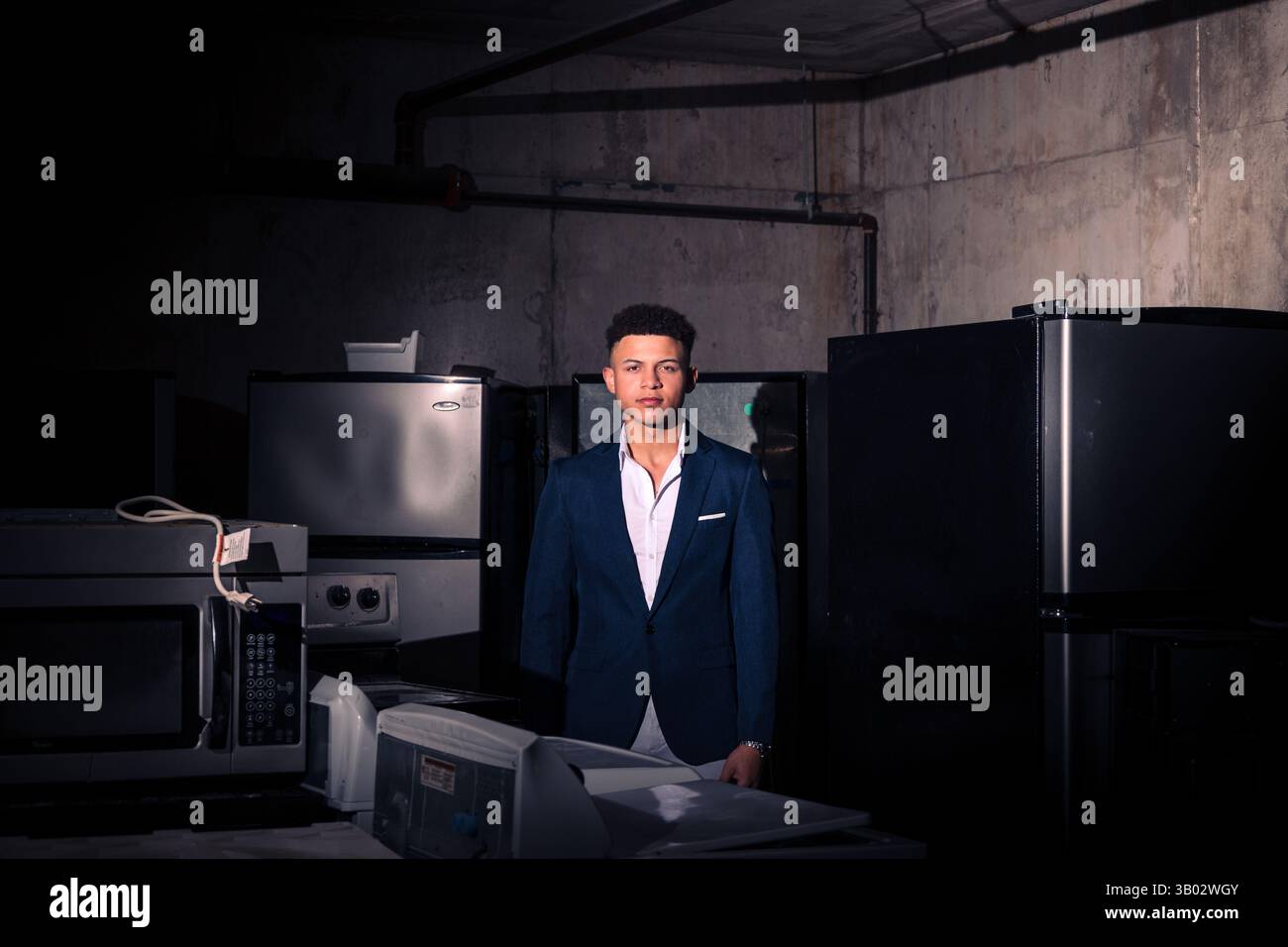 Mann in formeller Kleidung lehnt sich an Betonwand in dramatischem Licht und Schatten, industrieller Umgebung, Dallas, Texas, USA Stockfoto
