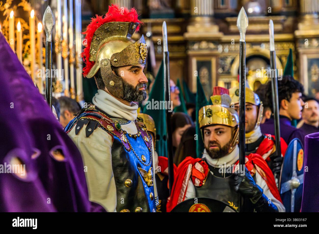 Vorbereitung auf die Karfreitagsprozession Camino del Calvario in der Iglesia Parroquial de El Salvador. Sie tragen aufwendige Kostüme, die an römische Soldaten erinnern und Speere und Schilde tragen. Die dunkelvioletten Stoffe stehen für Trauer und Hingabe. Calle San Vicente, Cuenca, Castilla-La Mancha, Spanien Stockfoto