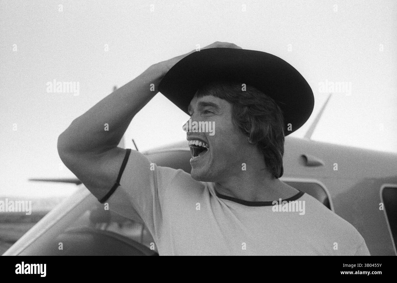 Juli 1979; Los Angeles, CA, USA; der professionelle Bodybuilder ARNOLD SCHWARZENEGGER trägt einen Cowboyhut auf einer windigen Landebahn, die vor dem kleinen Flugzeug seiner Freunde steht. Arnold, geboren in einem kleinen Dorf in Österreich, nahm schon in jungen Jahren das Krafttraining auf und stieg bald als Bodybuilding-Champion an die Spitze. Sein Einbruch in der Schauspielerei kam 1982 in dem Film Conan the Barbarian. Seit Conan hat Arnold eine lange Karriere als Schauspieler. Arnold war seit Anfang der 80er Jahre in der US-Politik aktiv und wurde seitdem als Gouverneur von Kalifornien gewählt Stockfoto