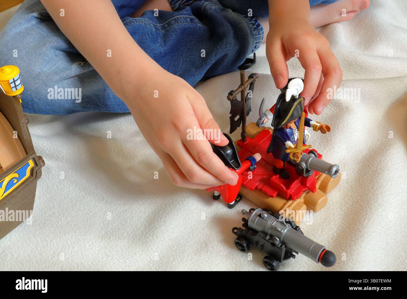 Ein Kind spielt mit playmobil-Piraten und britischen Rotwanzsoldaten. Kein Gesicht, nur Hände sichtbar. Stockfoto