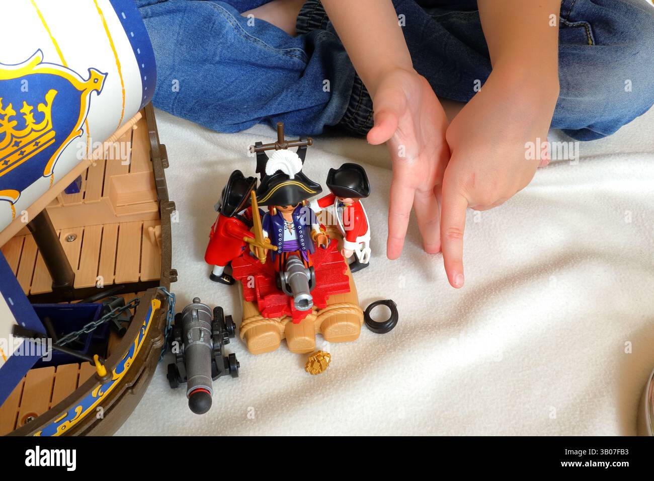 Ein Kind spielt mit playmobil-Piraten und britischen Rotwanzsoldaten. Kein Gesicht, nur Hände sichtbar. Stockfoto