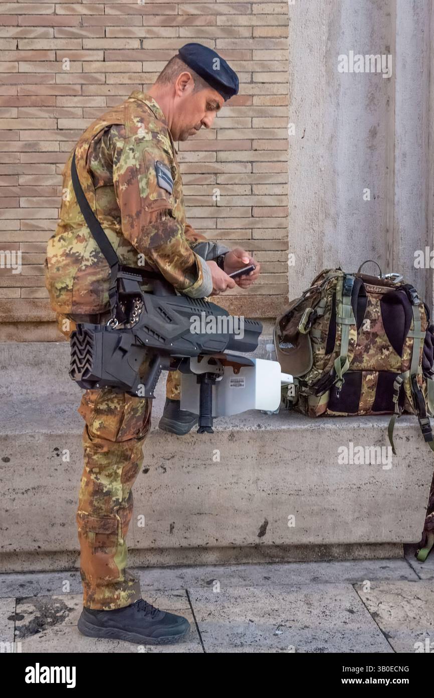Ein italienischer Soldat, der mit einem Drohnengewehr bewaffnet ist, bewacht den Petersplatz während der Hommage an die Leiche von Francesco Papst, Vatikanstaat, Rom, Italien Stockfoto