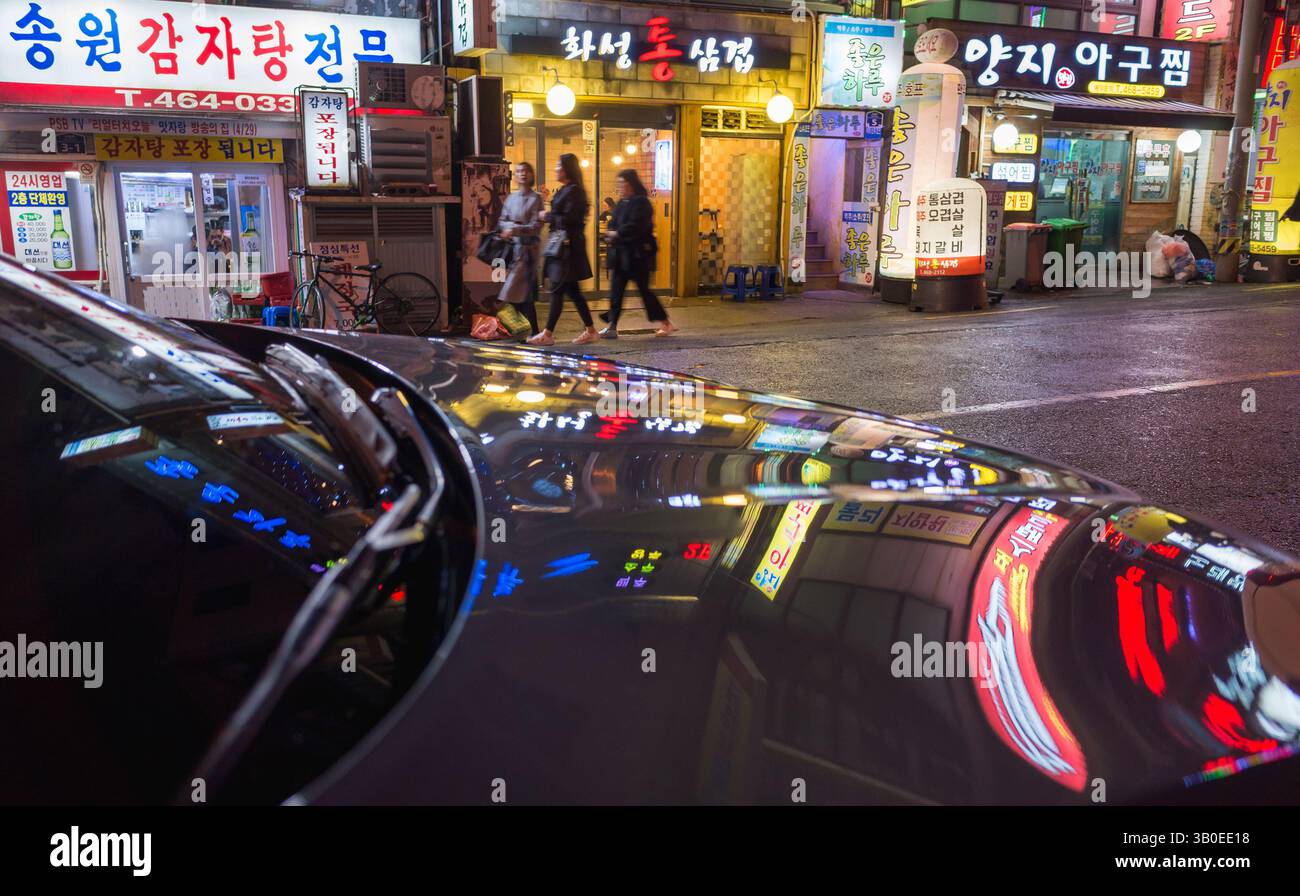 Busan, Südkorea - 19. März 2018: Hell beleuchtete Straßen bei Nacht bieten ein pulsierendes Stadtbild mit beleuchteten Schaufensterfronten und farbenfrohen Reflexen Stockfoto