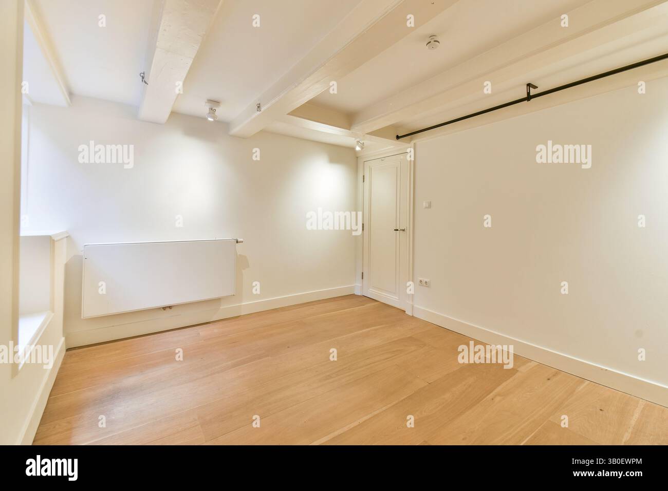 Ein geräumiges Interieur mit klaren Linien, weißen Wänden und warmem Holzfußboden schafft eine ruhige und moderne Umgebung, die perfekt für Entspannung und Kreativität ist. Stockfoto