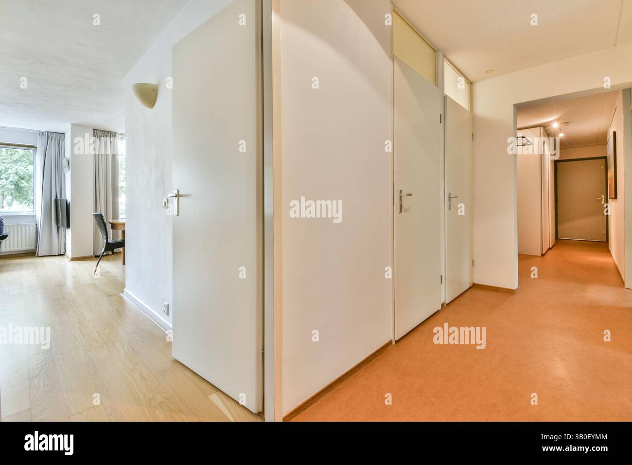 Geräumiger Flur mit modernen Designelementen und Tageslicht durch die Fenster, ergänzt durch minimalistische Einrichtung und neutrale Farbtöne. Stockfoto