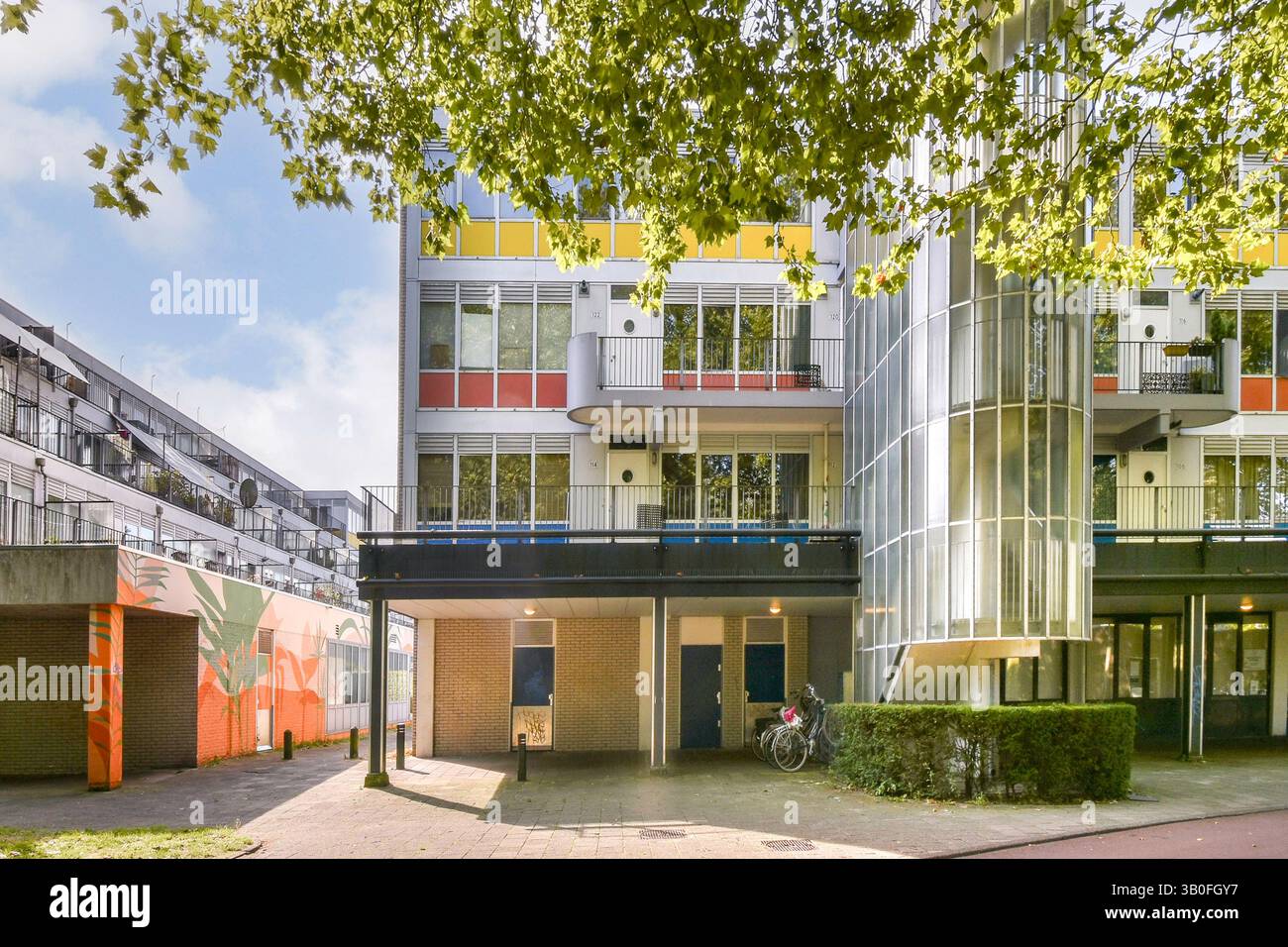 Ein modernes Gebäude mit moderner Architektur, großen Fenstern und Grün, in einer städtischen Umgebung. Das Design spiegelt innovatives urbanes Leben wider. Stockfoto