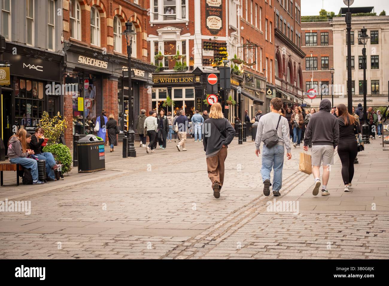 LONDON - 23. APRIL 2025: Junge Leute kaufen in offener Straßenansicht des Covent Garden-Viertels im Londoner West End ein. Stockfoto