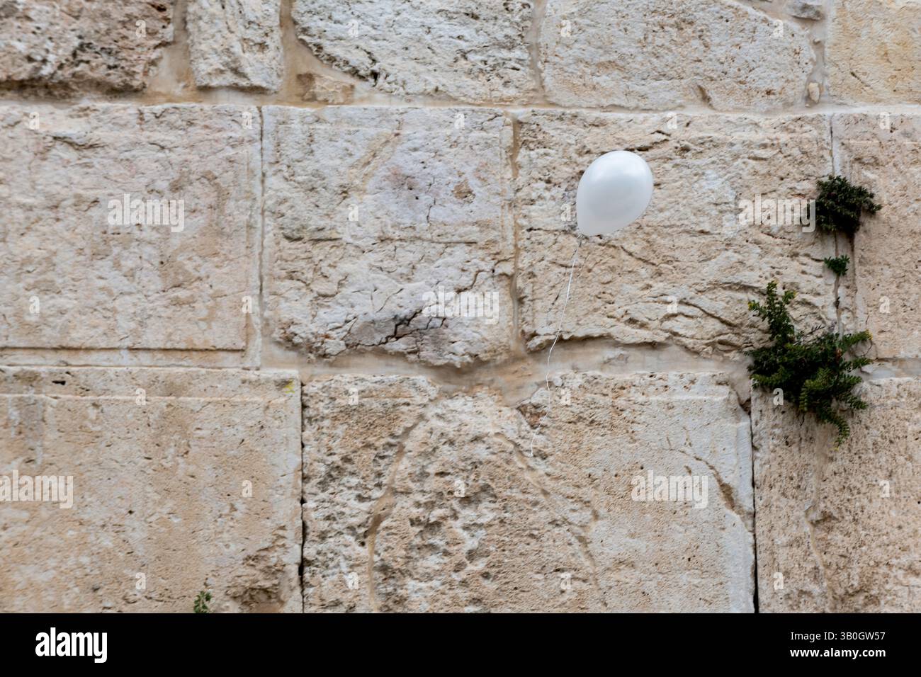 Ein weißer Ballon auf einer Schnur schwimmt vor den alten Steinen der Westmauer in der Altstadt von Jerusalem, Israel. Stockfoto