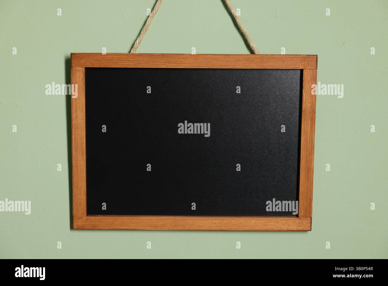 Eine leere kleine Tafel an hellgrüner Wand Stockfoto
